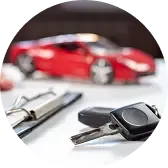 Ключи от автомобиля, лежащие на столе рядом с документами, на фоне размытого красного спортивного авто.