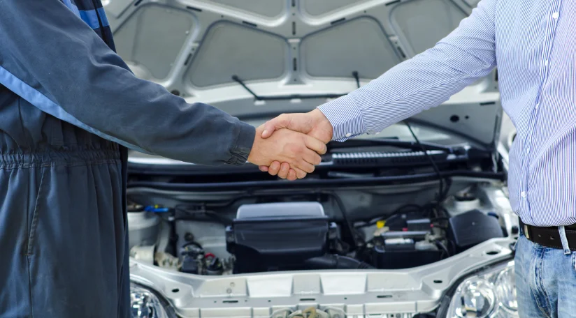 Работник сервиса приветствует рукопожатием клиента.