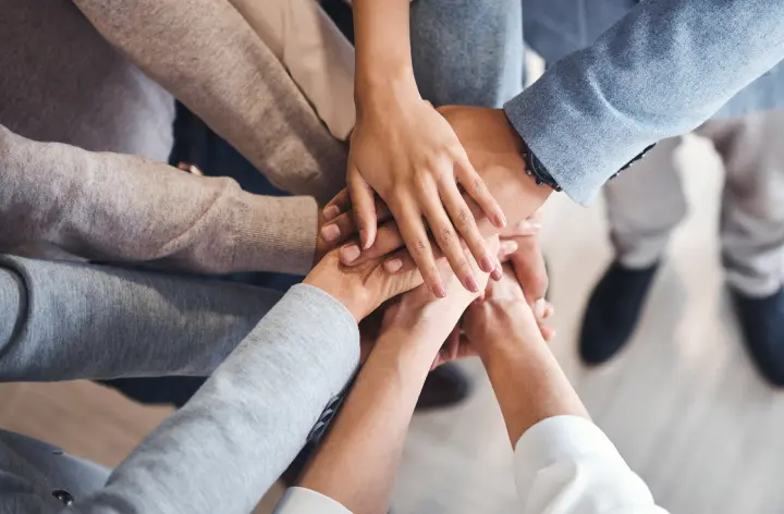 Люди объединяют руки в центре, символизируя единство и сотрудничество.