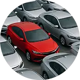 Красная машина стоит среди серых автомобилей на парковке.