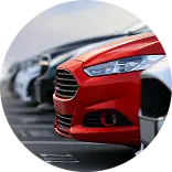 Красный автомобиль выделяется на фоне других машин на парковке.