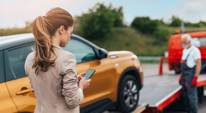 Девушка стоит на дороге. Ее автомобиль эвакуируют.