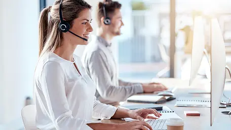 Мужчина и женщина в наушниках работают за компьютером в офисе колл-центра.