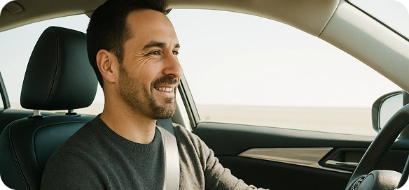 Улыбающийся мужчина за рулём автомобиля.
