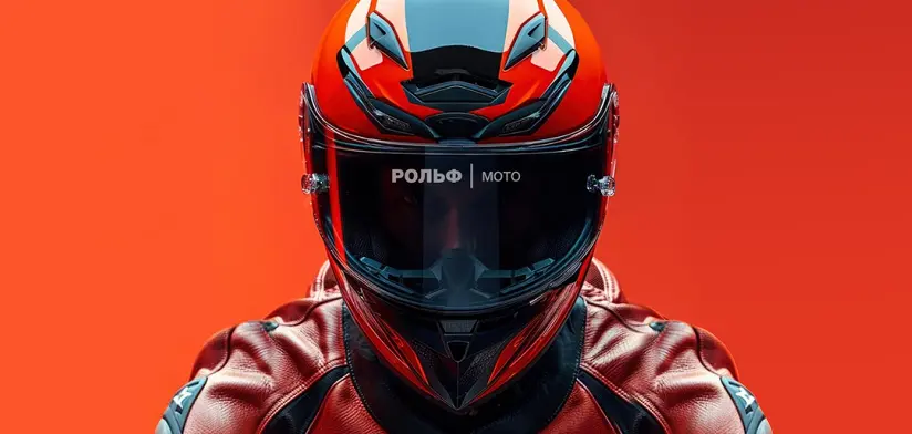 Человек в красном и черном мотошлеме и красной кожаной куртке на фоне оранжевой стены